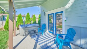Une terrasse couverte avec un jacuzzi, deux chaises bleues et un tapis à rayures.