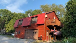 Une maison rouge à deux étages, avec un garage, un balcon et une véranda.