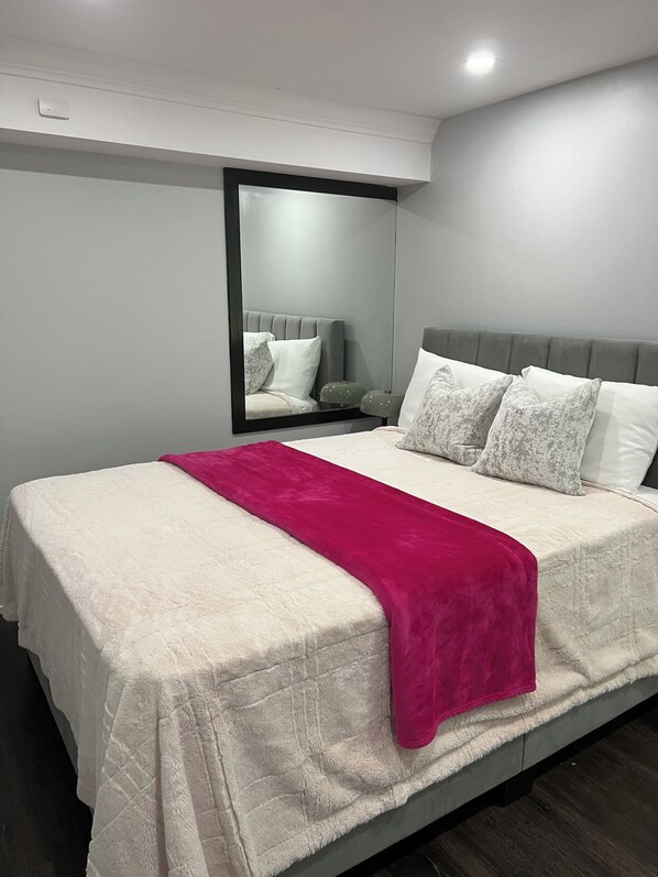 Une chambre à coucher moderne avec un grand lit, un miroir et une table de chevet.