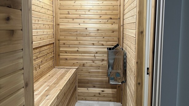 Eine Holzsauna mit Bänken und einer Glastür.
