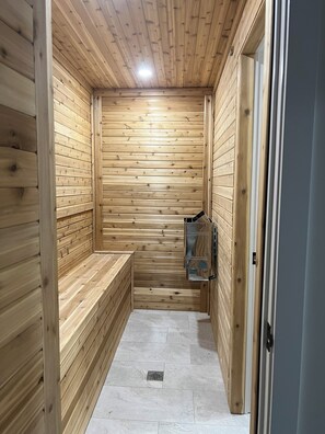 Un sauna en bois, doté de bancs et d’une armoire en verre.