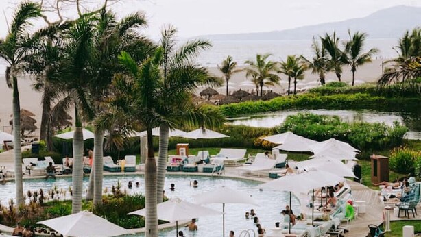 Ein Poolbereich eines Resorts mit mehreren Pools, Liegestühlen und Sonnenschirmen.