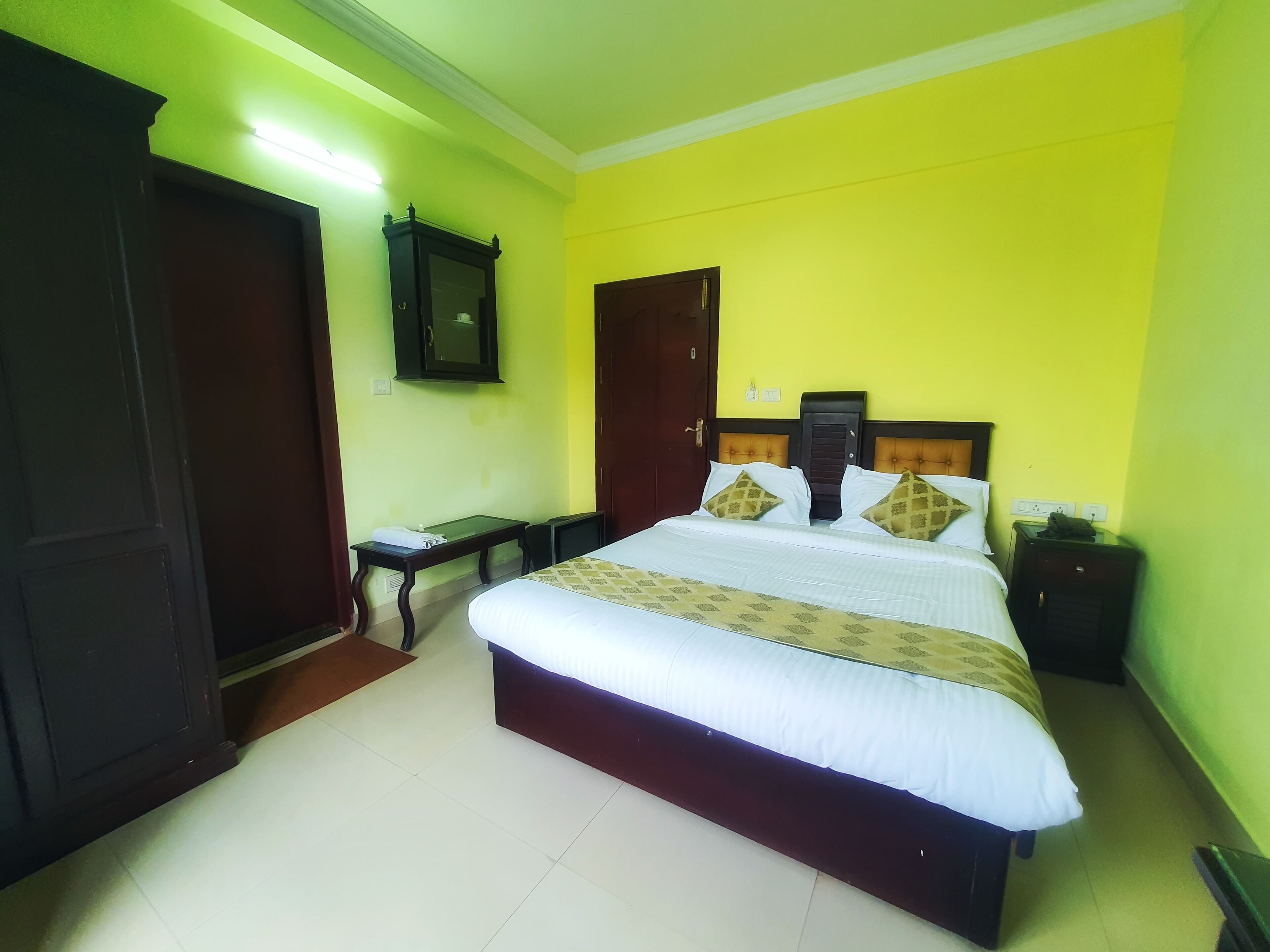 Un dormitorio ordenado con cama, mesita de noche y un espejo en la pared.