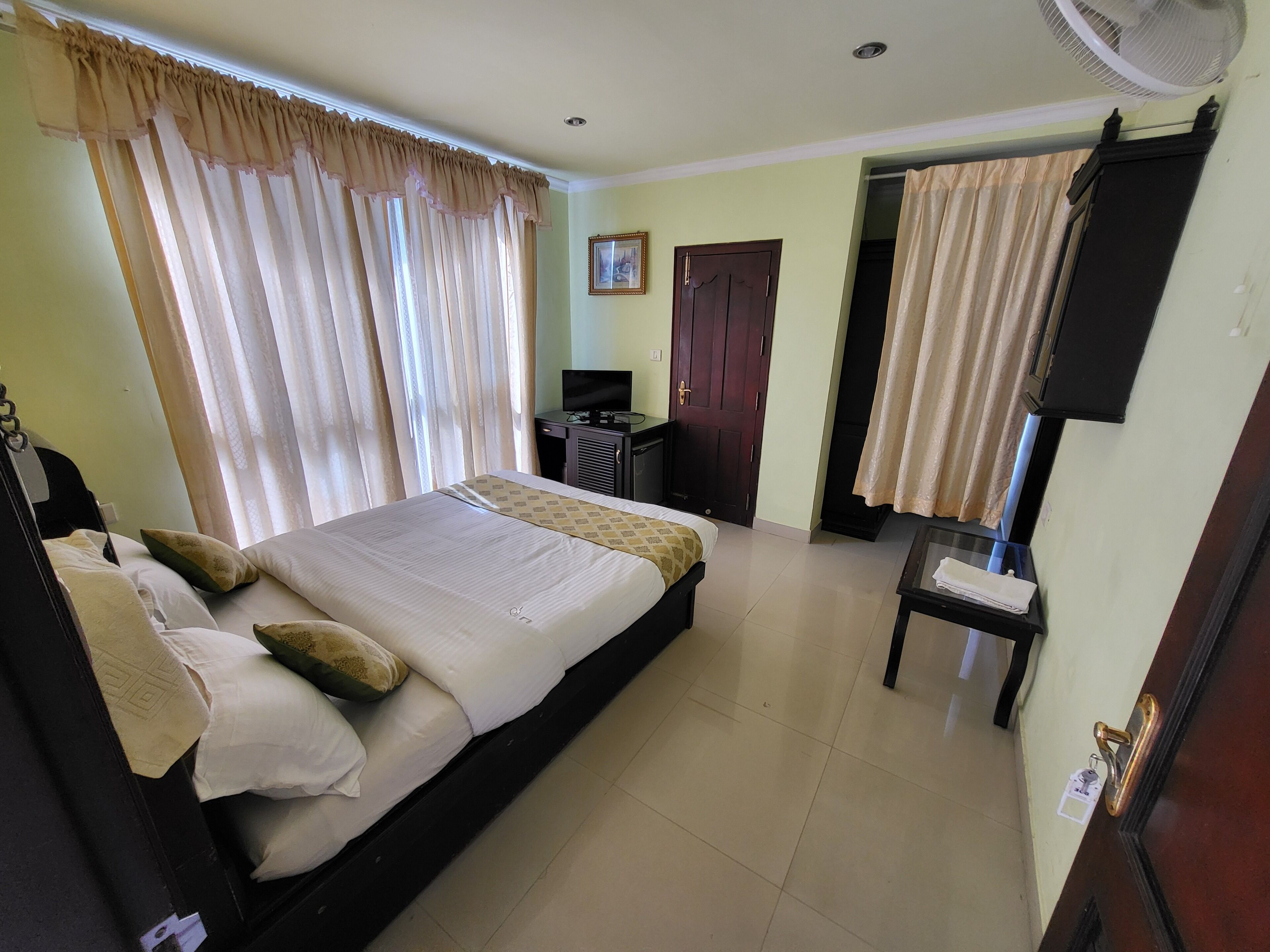 Una habitación de hotel con una cama, un escritorio, una silla, un televisor y una puerta.