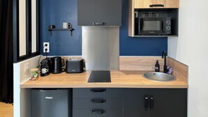 Cocina compacta con refrigerador, microondas, cafetera y pileta.