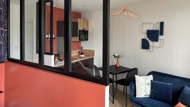 Un espacio moderno para vivir con área de cocina, mesa de comedor y sofá azul.