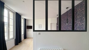 Una habitación con un ventanal grande, un radiador y un televisor montado en la pared.