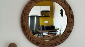 Een ronde spiegel met een structuurrijk frame aan een muur.