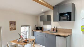 A compact kitchen with grey cabinets, a built-in microwave, and a sink.