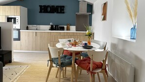 Een moderne keuken met een 'HOME' bord, een eettafel met stoelen en een vaas met bloemen.