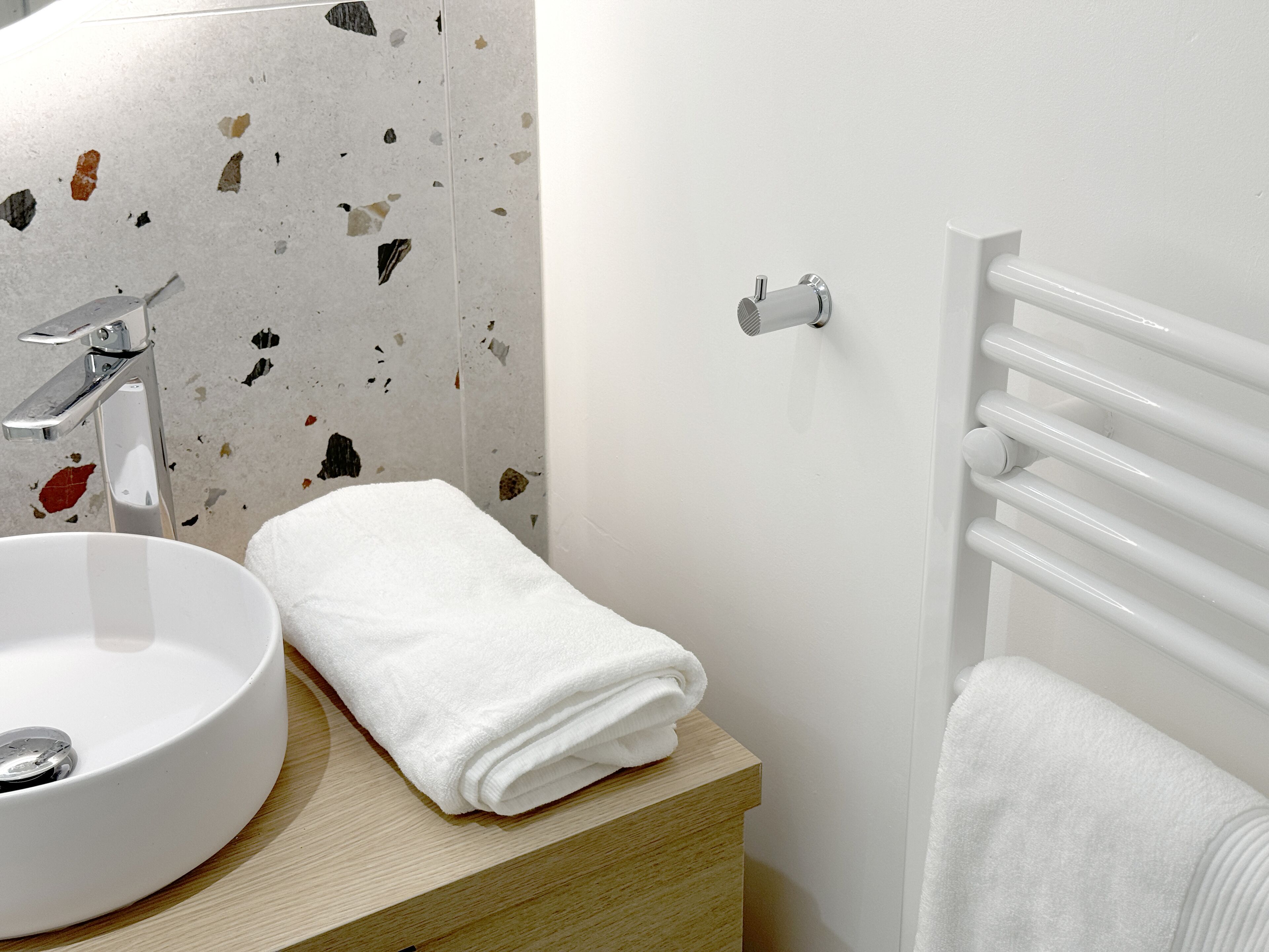 Une salle de bain avec un lavabo blanc, une serviette et un porte-serviettes blanc.