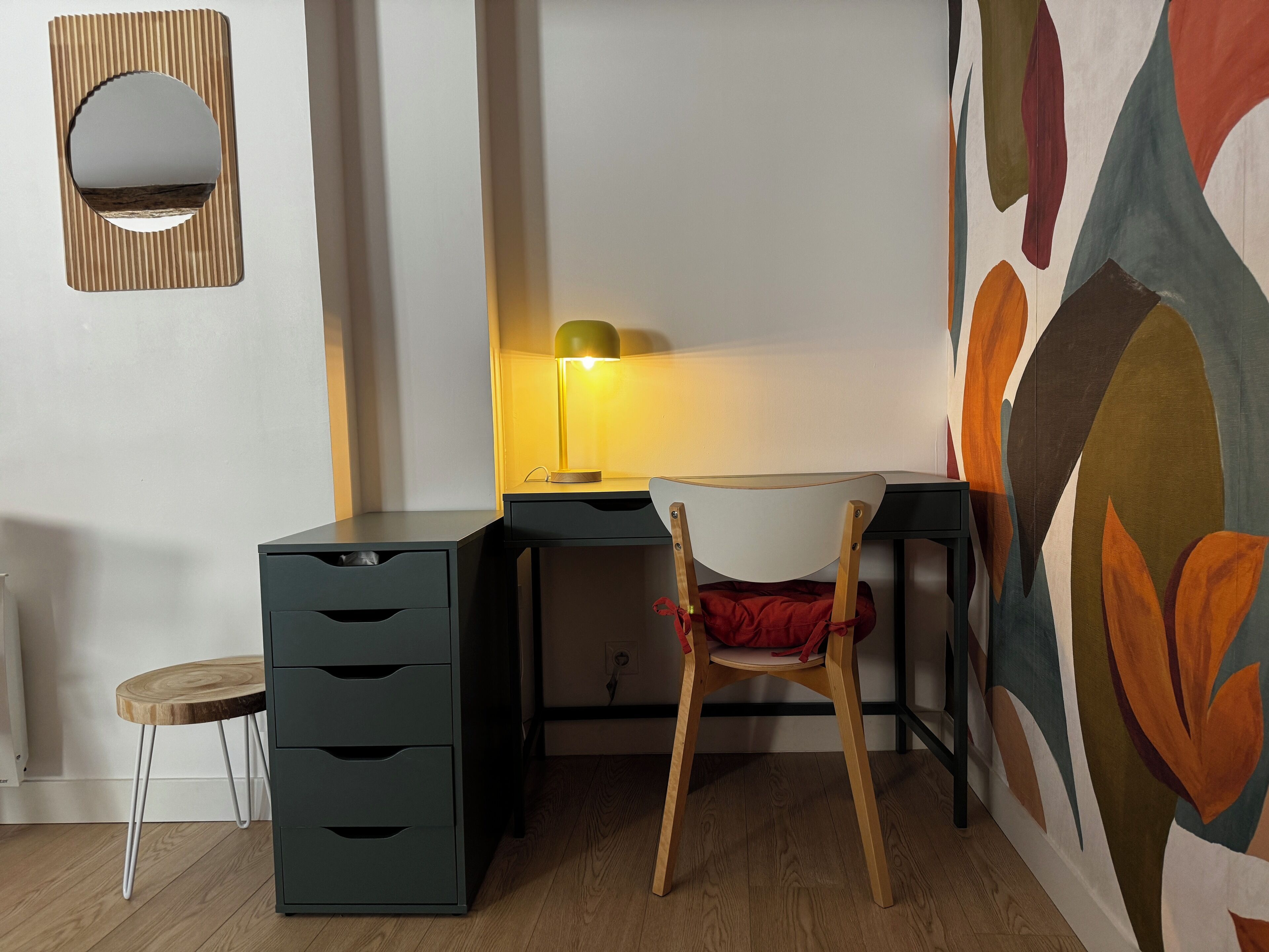 A corner room with a desk, chair, and a lamp.