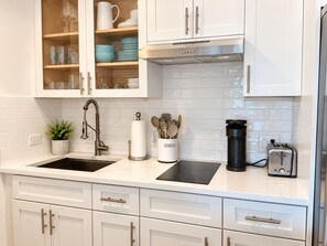A kitchen with white cabinets, a stainless steel range hood, a black toaster, and a utensil holder. - 1/1 Waterview Condo, Pool, Private Beach Access (Longboat Key)
