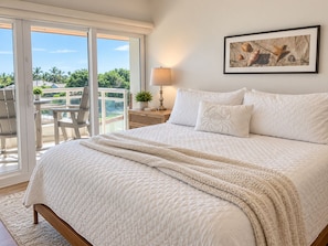 A bedroom with a large bed, a nightstand, a lamp, and a framed picture on the wall.