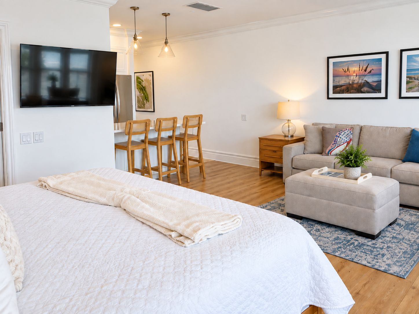 A modern bedroom with a large bed, a sofa, a coffee table, and a TV mounted on the wall.