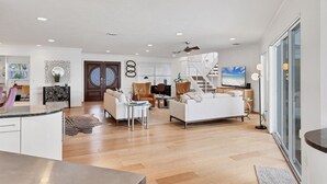 Zona d'estar àmplia amb disseny modern, que inclou un sofà blanc gran, una taula de menjador i una escala que condueix a una planta superior.