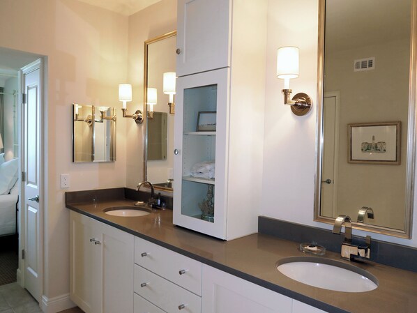 A bathroom with two sinks, a large mirror, and wall-mounted lights.