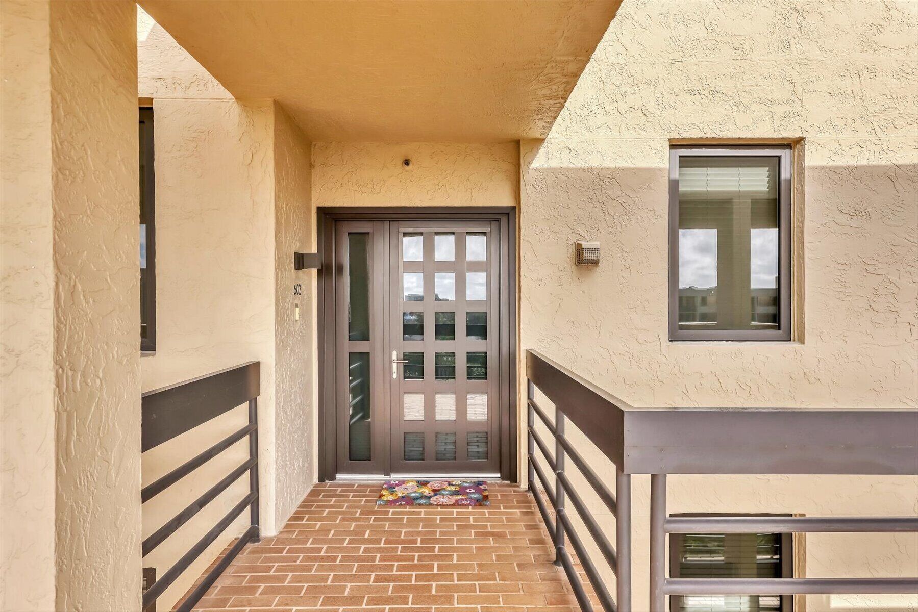 A narrow, enclosed hallway with a door leading to a balcony. The hallway has a textured wall and a metal railing on one side.