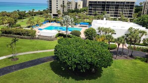 A resort with a large pool, palm trees, and a view of the ocean. - 2/2 Condo BEACH VIEW, Pool, Fitness, Tennis (Longboat Key)