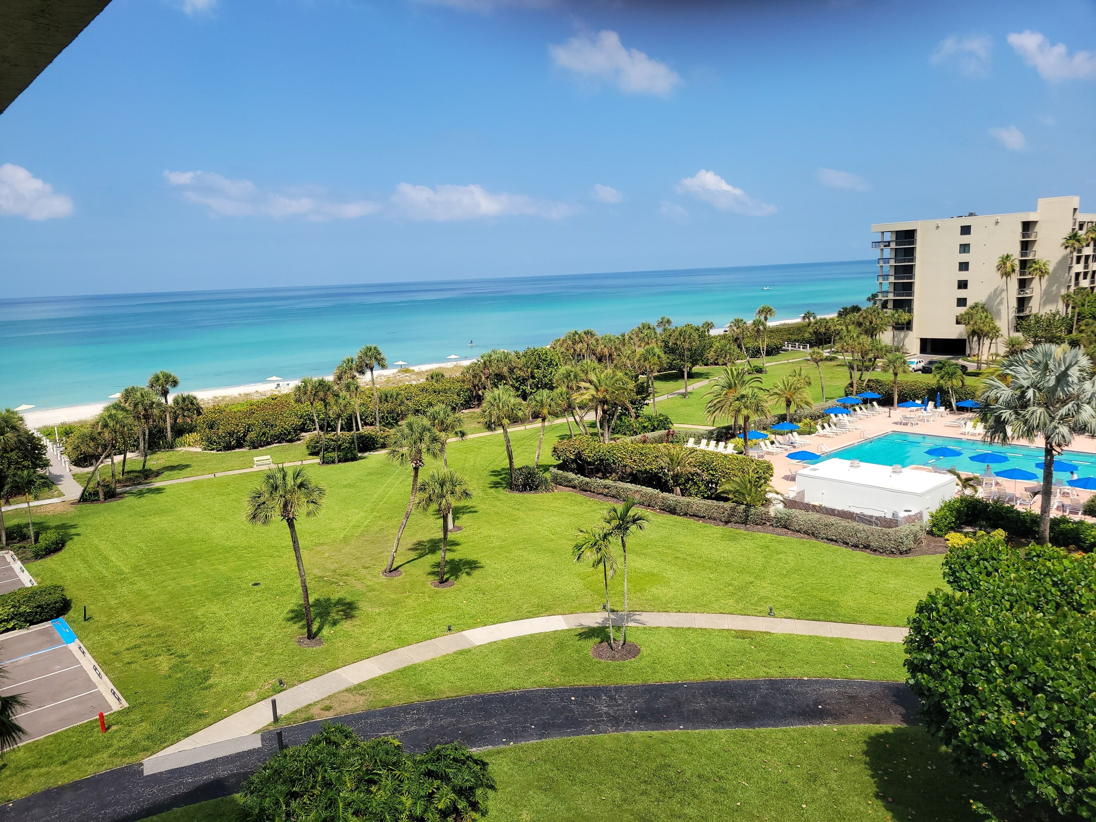 Een resort met een zwembad, palmbomen en uitzicht op de oceaan.