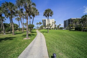 Stroll through lush gardens to a modern building with balconies.