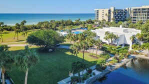 An aerial view of a resort with a pool, palm trees, and a beach.