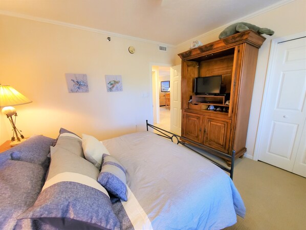 A bedroom with a bed, a TV, and a wooden cabinet.