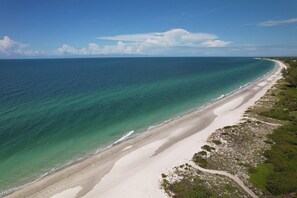 A coastal landscape with a sandy beach and a clear view of the ocean.