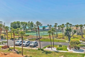 A parking area with several cars, a tennis court, and palm trees. - 2/2 Bay Front Condo, Pool, Private Beach Access (Longboat Key)