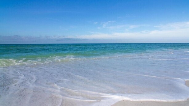 Una playa con agua azul cristalina y una orilla arenosa.