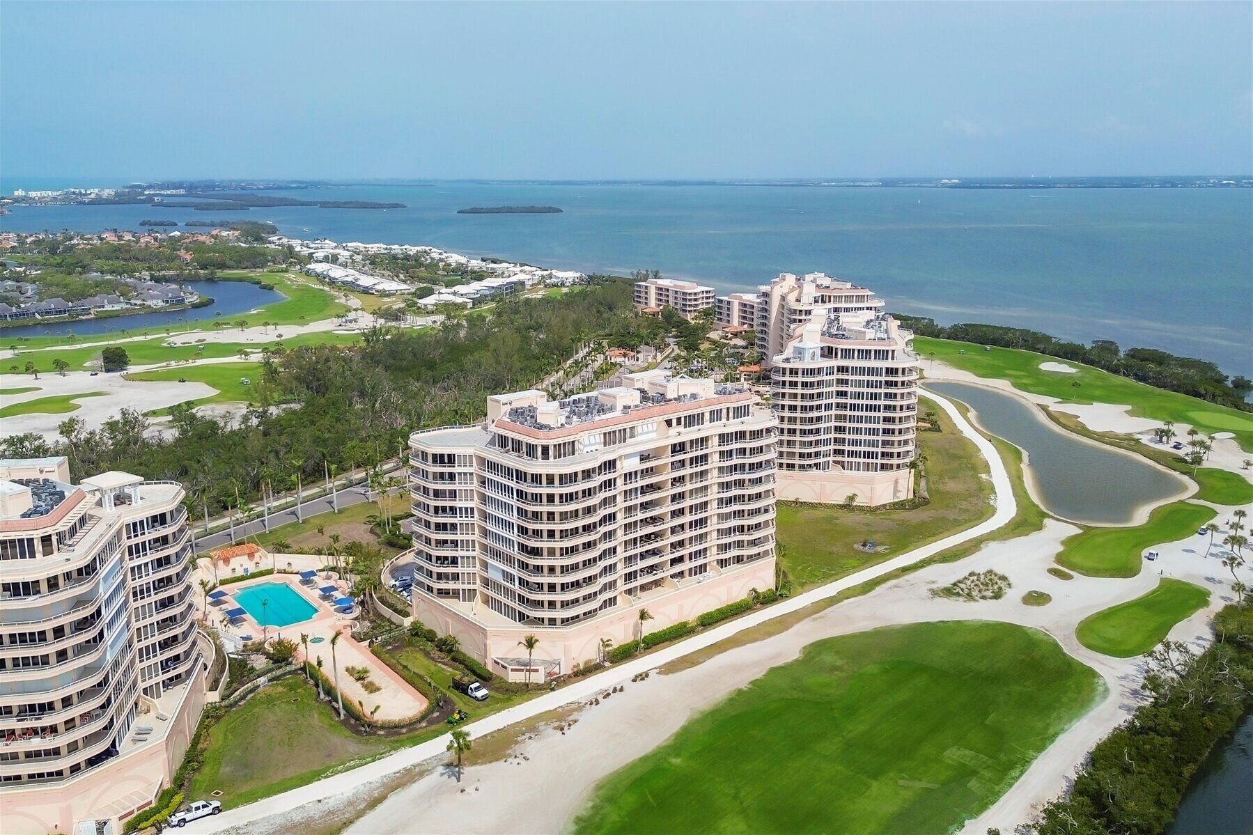 A high-rise hotel with multiple balconies, a pool, and a golf course nearby.