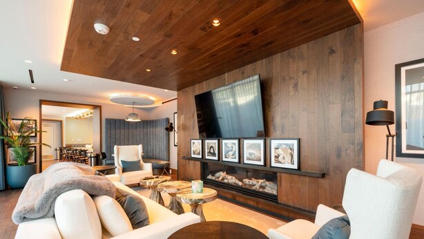 A modern living room with a wooden ceiling, a fireplace, and a flat-screen TV mounted on the wall. There are several seating areas with sofas and chairs, and a dining area in the background. - Deer Valley East I Walk to Jordanelle Gondola I Hot Tub I Arcade (Park City)