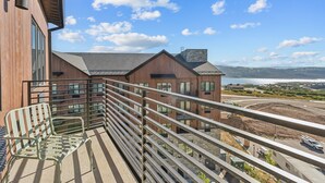 A balcony with a metal railing overlooking a construction site and a view of a building with large windows and a wooden facade. - Deer Valley East I Walk to Jordanelle Gondola I Hot Tub I Arcade (Park City)
