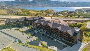 A multi-story hotel with a parking lot and a view of a lake and mountains. - Deer Valley East I Walk to Jordanelle Gondola I Hot Tub I Arcade (Park City)