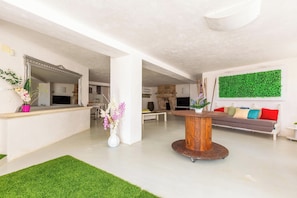A spacious living area with a round wooden table, a sofa with colorful cushions, a large mirror, and a green wall decoration. - 4123 Dimora Giove by Barbarhouse (Taviano)
