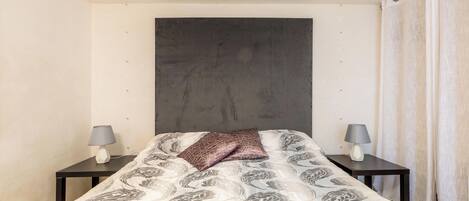 Un dormitorio con una cama, dos mesitas de noche y un cabecero.