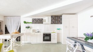 Eine moderne Küche mit weißen Schränken, einem eingebauten Backofen und einem Essbereich mit Tisch und Stühlen.