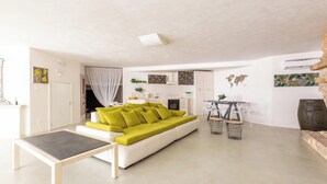 Ein modernes Wohnzimmer mit einem grünen Sofa, einem kleinen Tisch und einem Küchenbereich im Hintergrund.