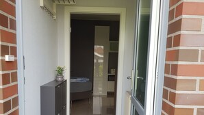 Un pasillo estrecho que conduce a un dormitorio con cama, cómoda y una pequeña planta.