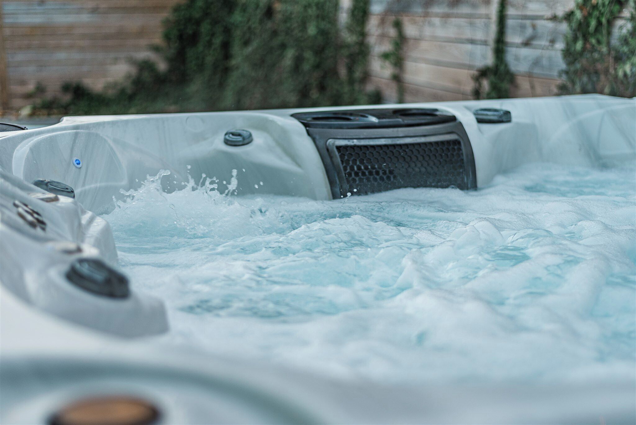 A hot tub with water jets, a control panel, and a textured cover.