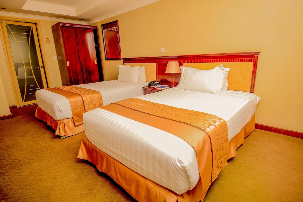 A hotel room with two beds, a wardrobe, and a mirror.