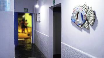Un couloir orné d’une décoration murale représentant des poissons, un panneau indiquant une sortie et une porte menant à une autre pièce.