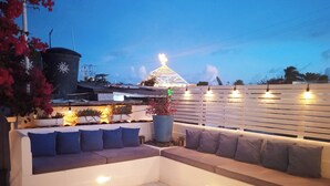 A modern outdoor seating area with a white sofa and blue cushions, surrounded by potted plants and a decorative fence. - Posada Lagunita by Mediterraneo (Los Roques)