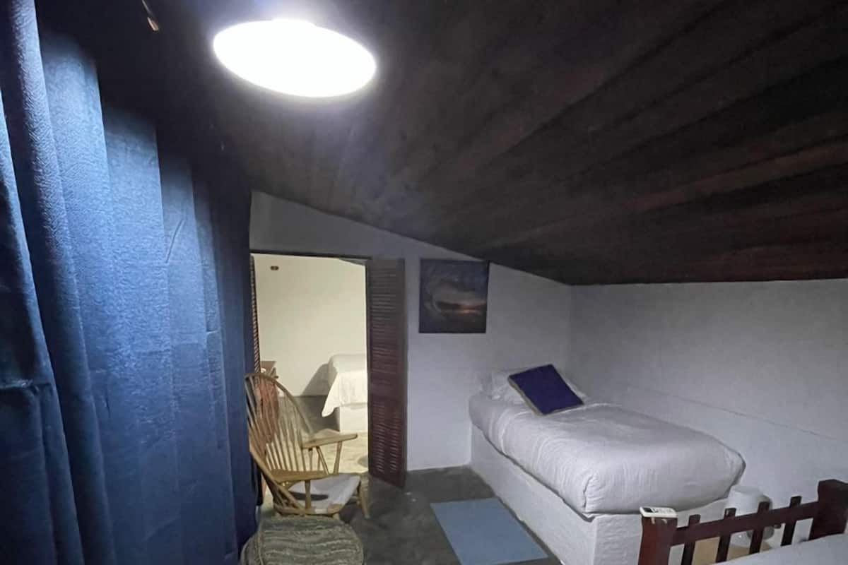 Une petite chambre avec deux lits, une chaise en bois et une petite table.