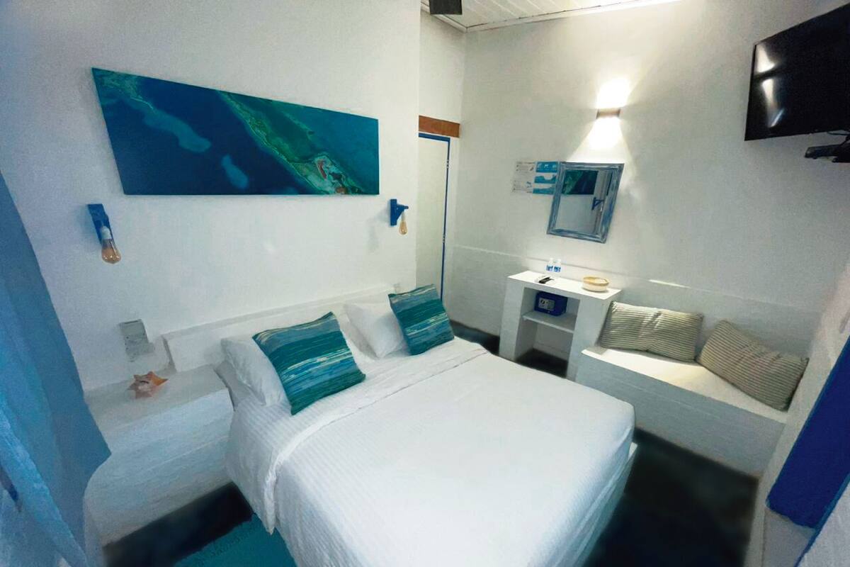 Une chambre d’hôtel de taille réduite, comprenant un lit, un petit bureau, un miroir et un téléviseur.