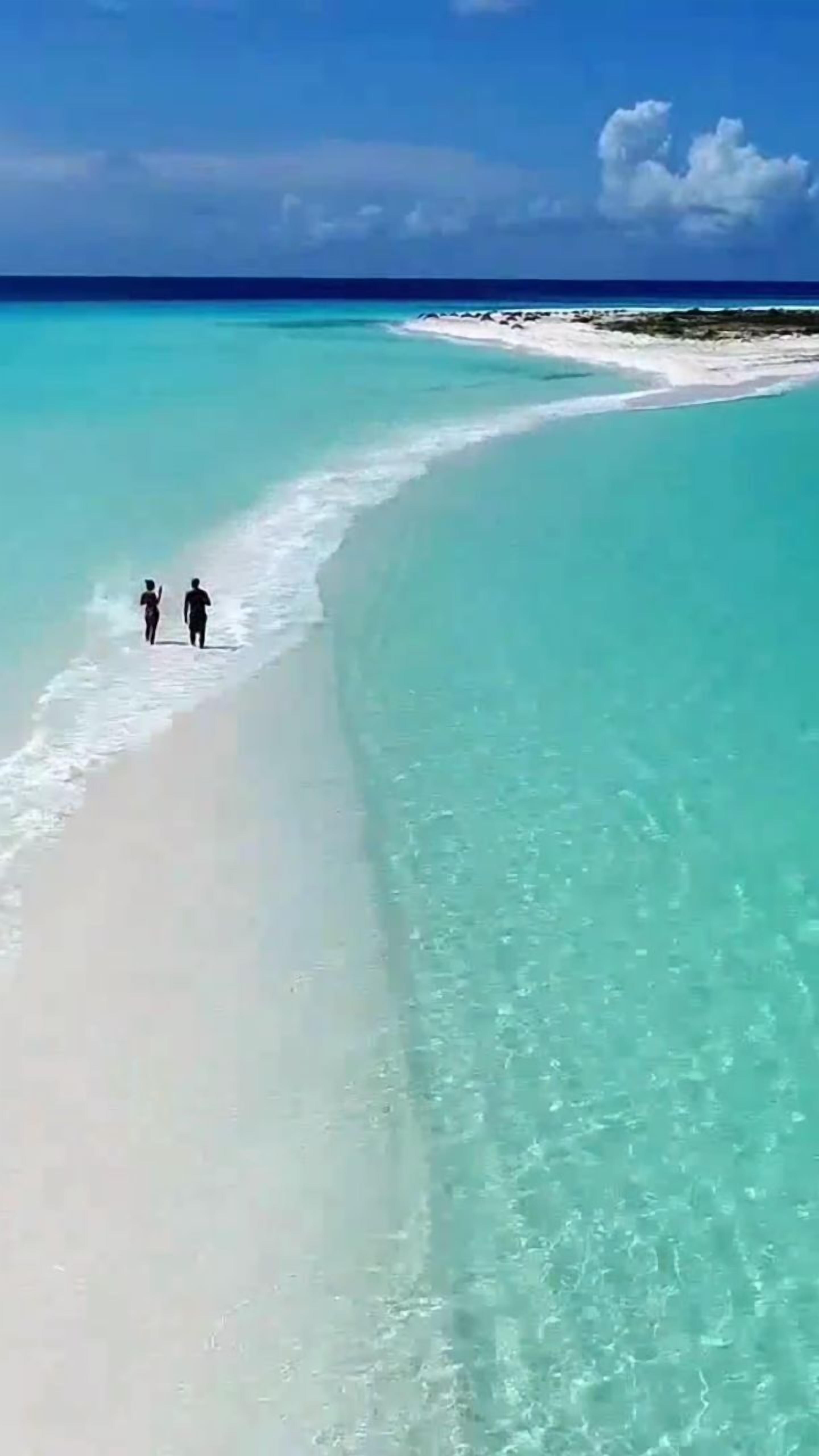 Een strand met helder turquoise water en een wit zandstrand.