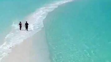 Een strand met helder turquoise water en een wit zandstrand.