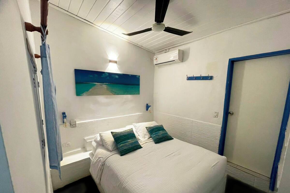 Une chambre d’hôtel avec un lit, un tableau, un appareil de climatisation et une porte.