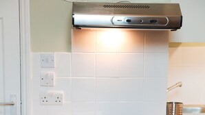 A kitchen with white cabinets, a wooden countertop, and a stainless steel range hood. - Sunlight Studio (London)