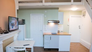 A compact kitchen with a dining area, a microwave, a stove, and a sink. - Sunlight Studio (London)